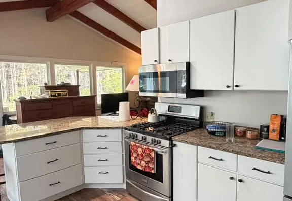White painted kitchen cabinets beneath exposed wood beams