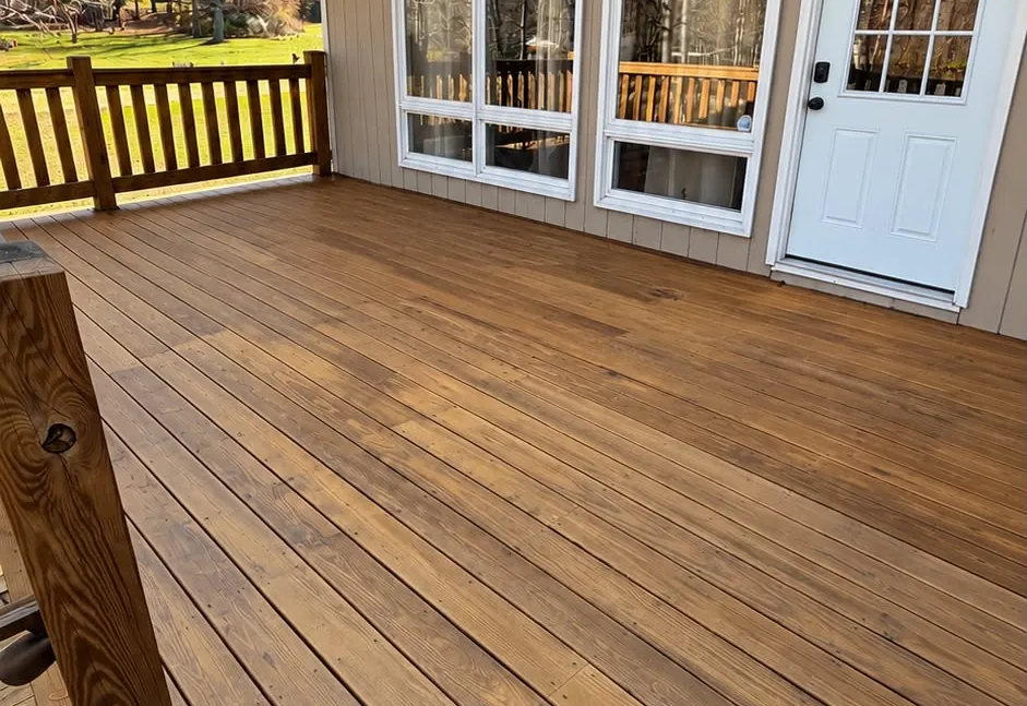 Finished golden wood deck beside a home with white windows