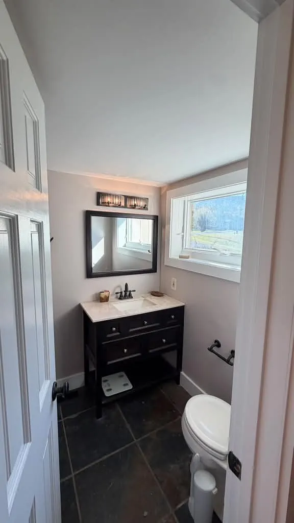 Bathroom with light painted walls, white trim and a dark vanity