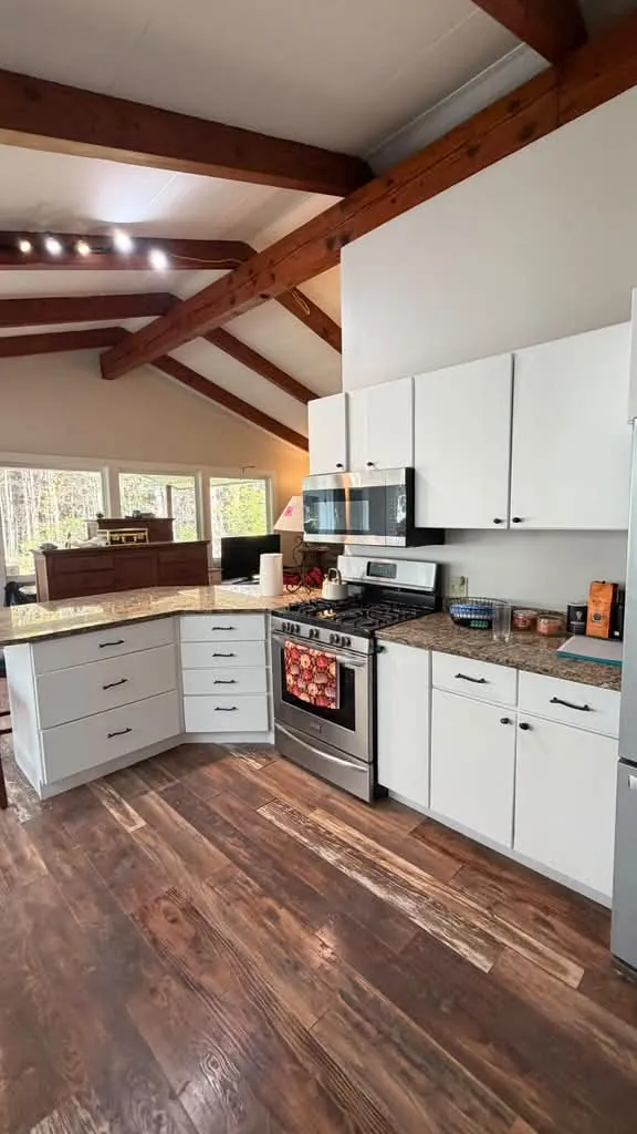 White painted kitchen cabinets with wood beams and wood-look flooring